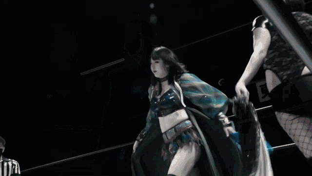 a woman in a blue and green dress is dancing in a dark room