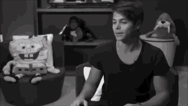 a black and white photo of a man sitting in front of stuffed animals including spongebob