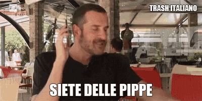 a man is talking on a cell phone while sitting at a table .