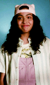 a woman wearing a cat hat and overalls smiles