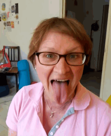 a woman wearing glasses and a pink shirt has her tongue hanging out