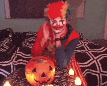 a person dressed as a clown is sitting on a bed next to a pumpkin