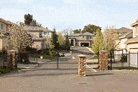 a gated entrance to a residential neighborhood with houses in the background and a gate in the foreground .