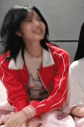 a woman wearing a red jacket is smiling and laughing