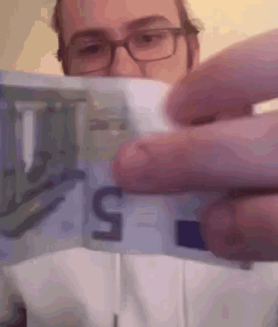 a man wearing glasses is holding a 5 euro bill