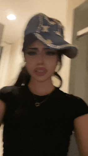 a woman wearing a hat and a black shirt is standing in a room .