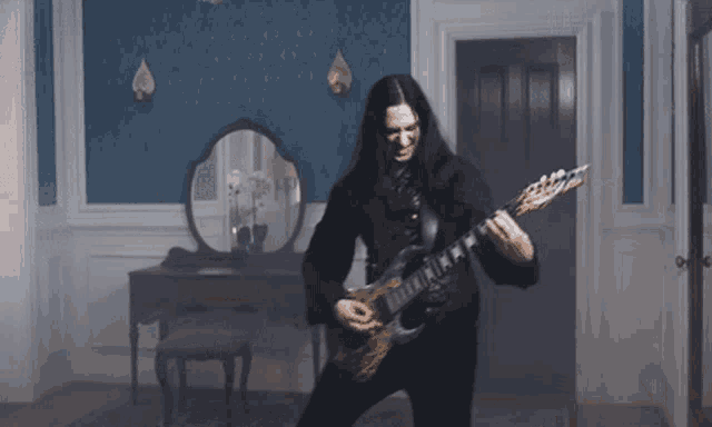 a man plays a guitar in a room with a mirror