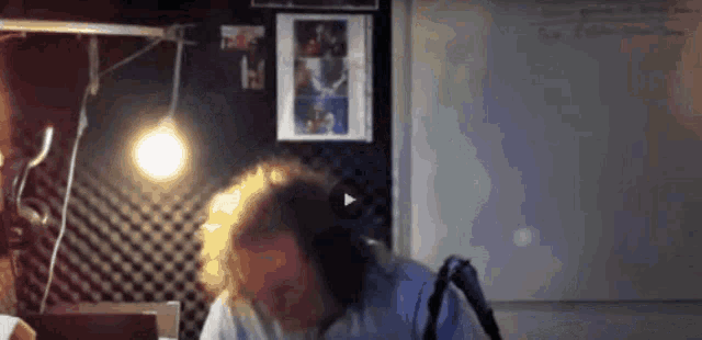 a man with curly hair is sitting in front of a white board with a picture of a woman on it