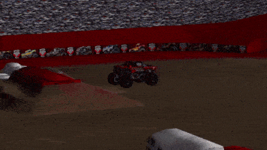 a monster truck is jumping over a wall in a stadium