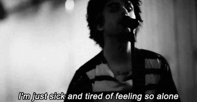 a man singing into a microphone with the words " i 'm just sick and tired of feeling so alone " next to him