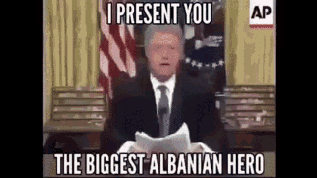 a man in a suit and tie is giving a speech and the caption says i present you the biggest albanian hero