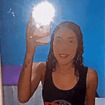 a woman is taking a selfie in front of a mirror while holding a light bulb in her hand .