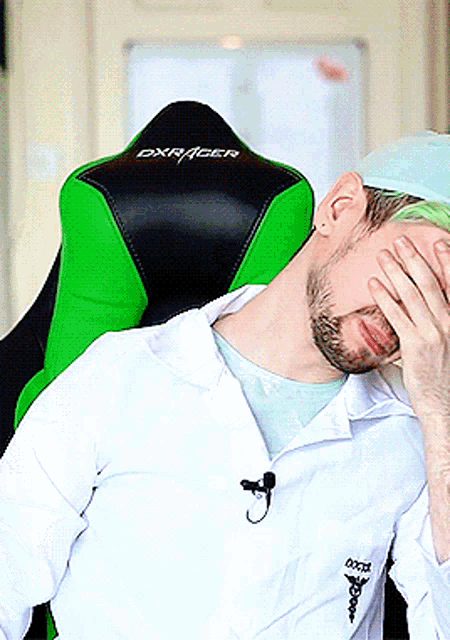 a man with green hair is sitting in a green dxracer gaming chair