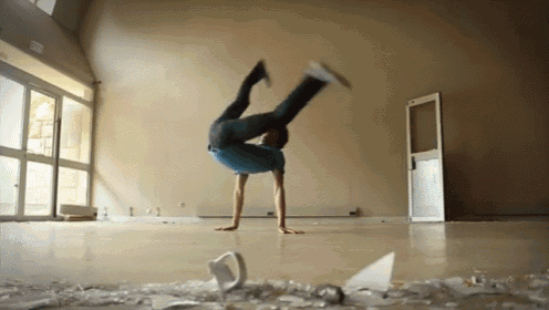a man in a blue shirt is doing a handstand in a room