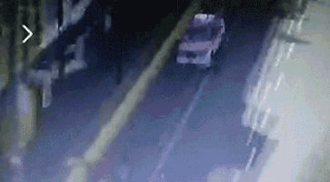 a car is driving down a street at night with a building in the background .