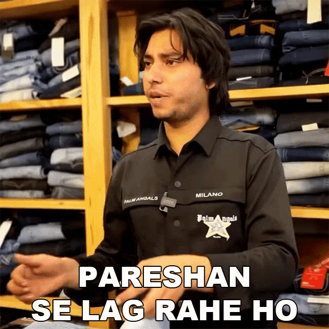 a man wearing a palm angels shirt stands in front of a display of jeans