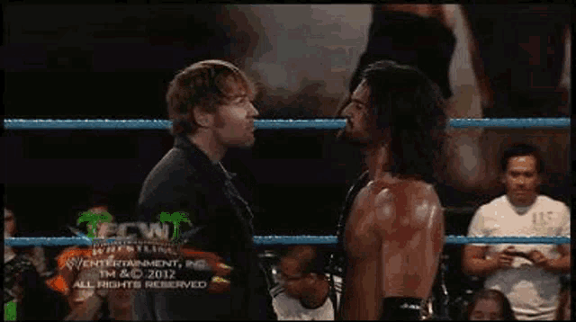a man is standing in a wrestling ring with a crowd watching .
