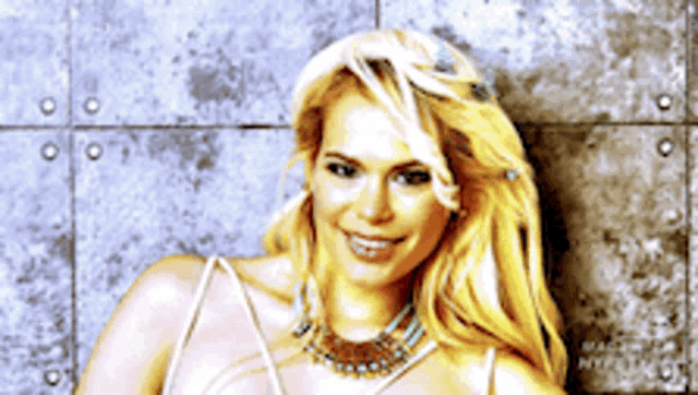 a blonde woman wearing a white dress and a necklace