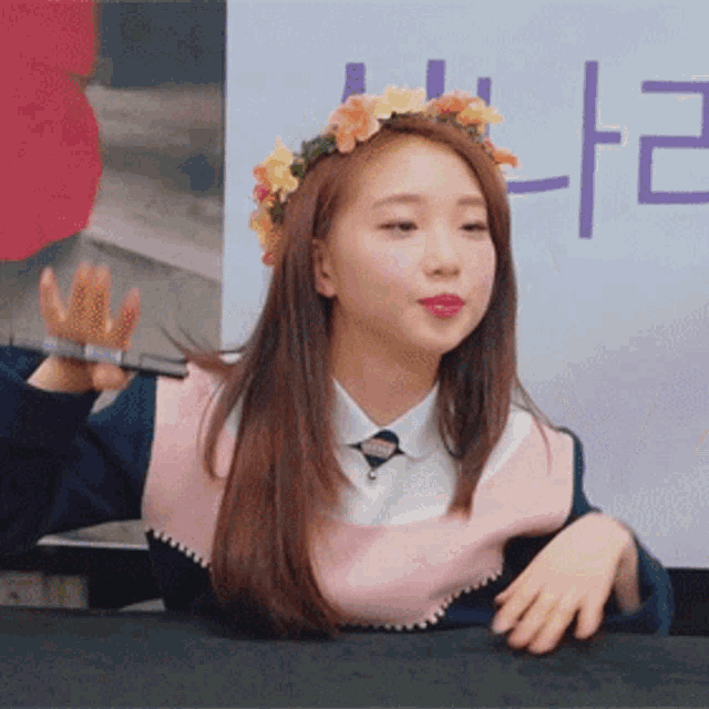 a woman with a flower crown on her head is sitting at a table
