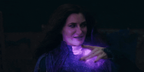 a woman is holding a purple object in her hand in the dark .