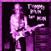 tommy bolin is playing a guitar in front of a stack of amps