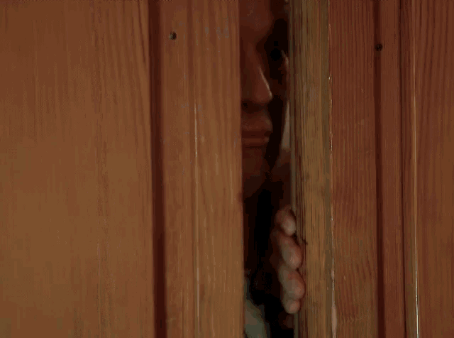 a bald man is looking through a doorway and smiling
