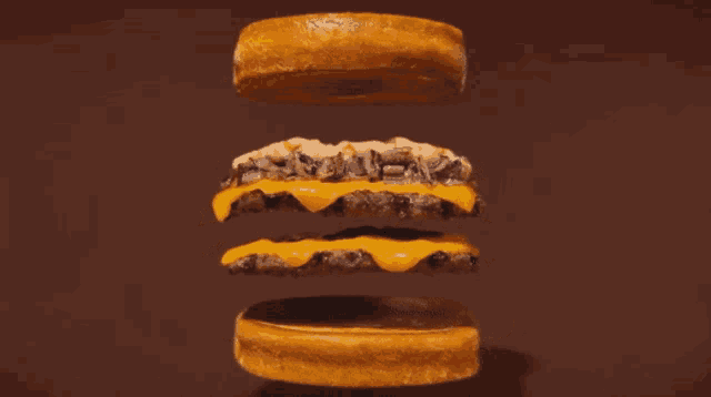 a close up of a hamburger with cheese and mushrooms on a brown background