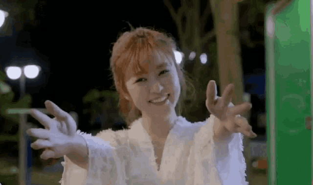 a woman in a white dress is holding her hands out towards the camera .