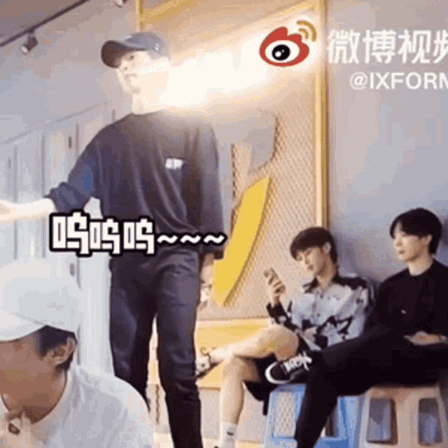 a group of young men are sitting on stools in a room with chinese writing on the wall