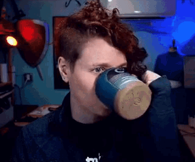 a woman with curly hair is drinking from a cup with the letter t on it
