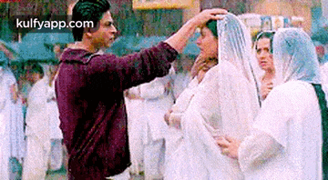 a man is putting his hand on a woman 's head in front of a crowd .