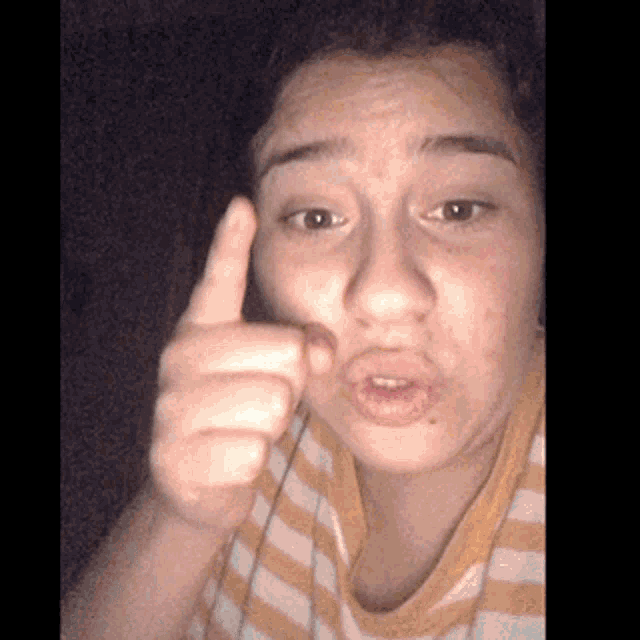 a woman in a yellow and white striped shirt is making a funny face