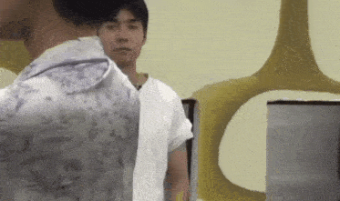 a man in a white shirt is standing next to another man in a floral shirt .
