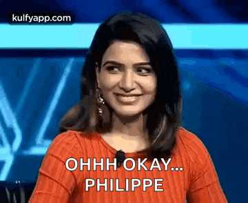 a woman in a red sweater is smiling and talking to a microphone .