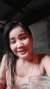 a woman is holding a glass of water in her hand and smiling .