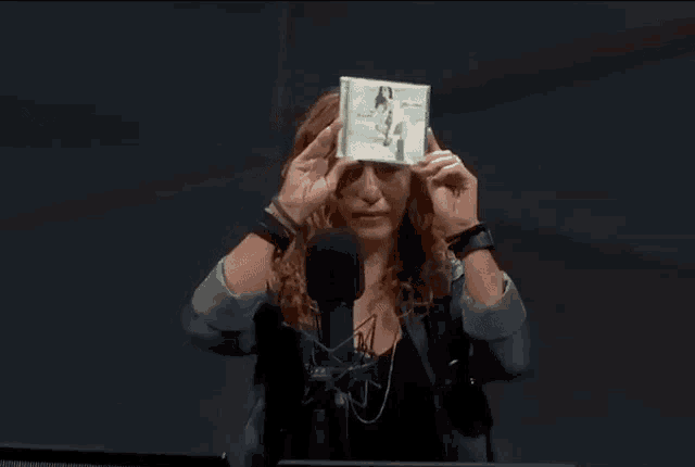 a woman in front of a microphone is holding a cd with a picture of a woman on it