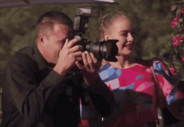 a man is taking a photo of a woman with a camera
