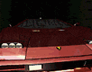 a red sports car is parked in a dark room with the hood up