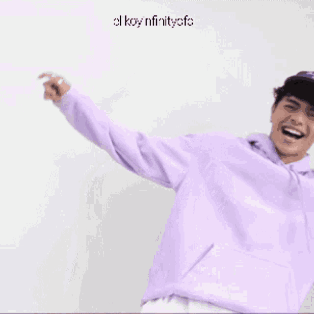 a young man wearing a purple hoodie and a blue hat is smiling