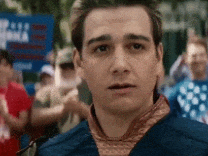 a man in a blue jacket is standing in front of a crowd of people holding a sign that says freedom