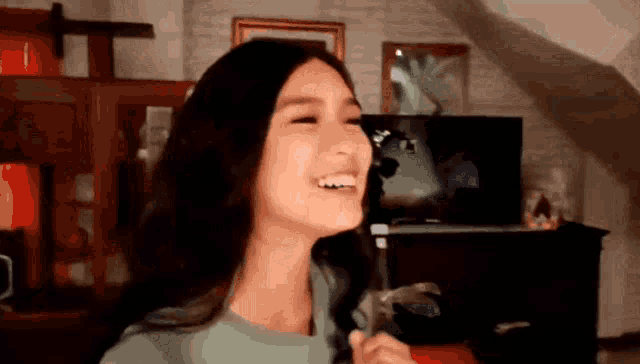 a woman is laughing in a living room with her mouth open .