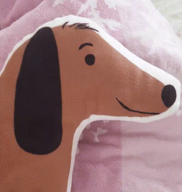 a brown and white pillow in the shape of a dachshund is sitting on a bed .