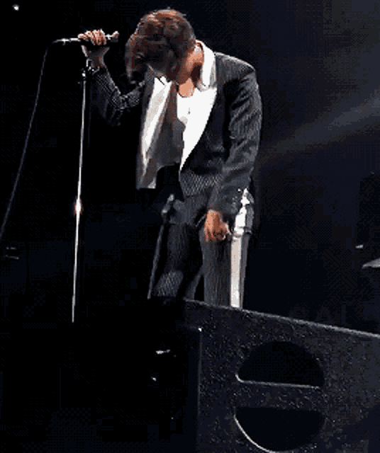 a man in a suit singing into a microphone on a stage