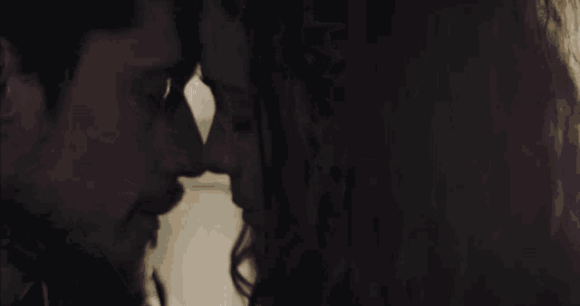 a close up of a man and woman kissing in the dark