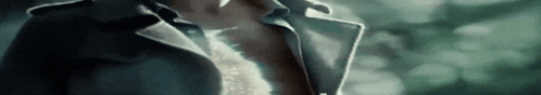 a close up of a person 's neck and chest in a dark room with trees in the background .