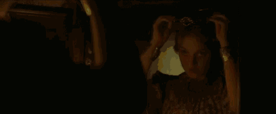 a woman is adjusting her hair in front of a mirror in the dark .