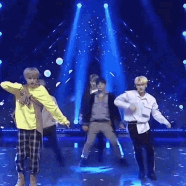 a group of young men are dancing on a stage in front of a blue background .