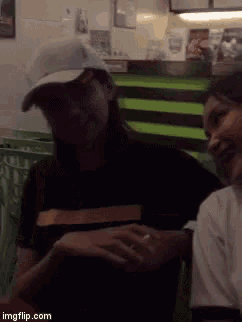 a woman wearing a hat is sitting next to another woman in a restaurant