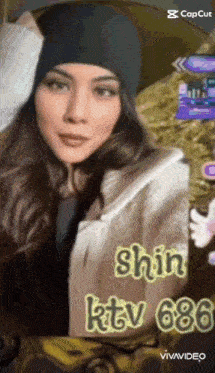 a woman wearing a hat and a jacket is standing in front of a sign that says shin ktv 686