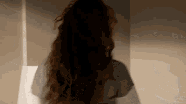 a woman with long red hair is standing in front of a white wall .